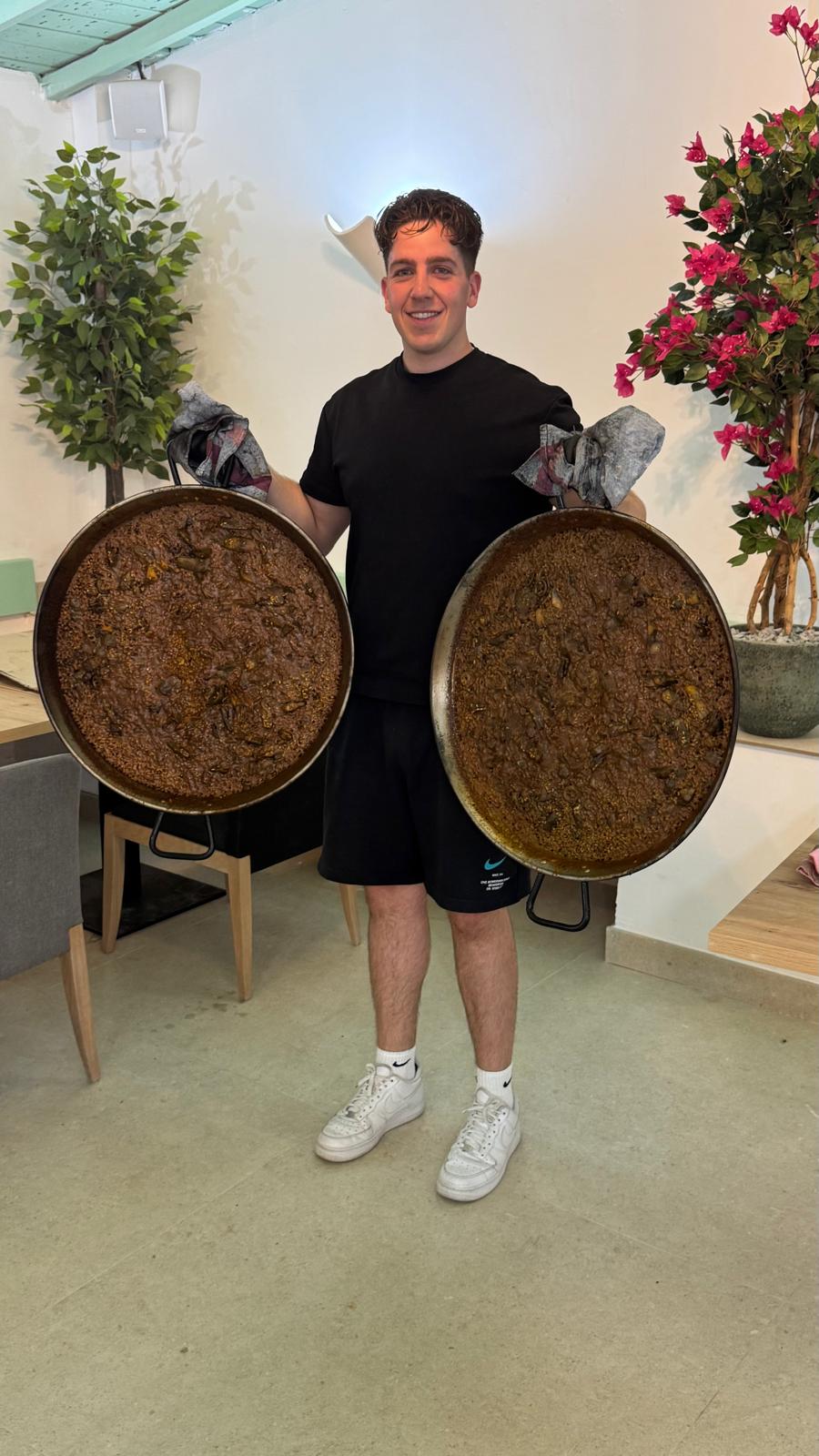Benji, chef de Los Pinochos, con dos paellas en la sala del restaurante en Simancas