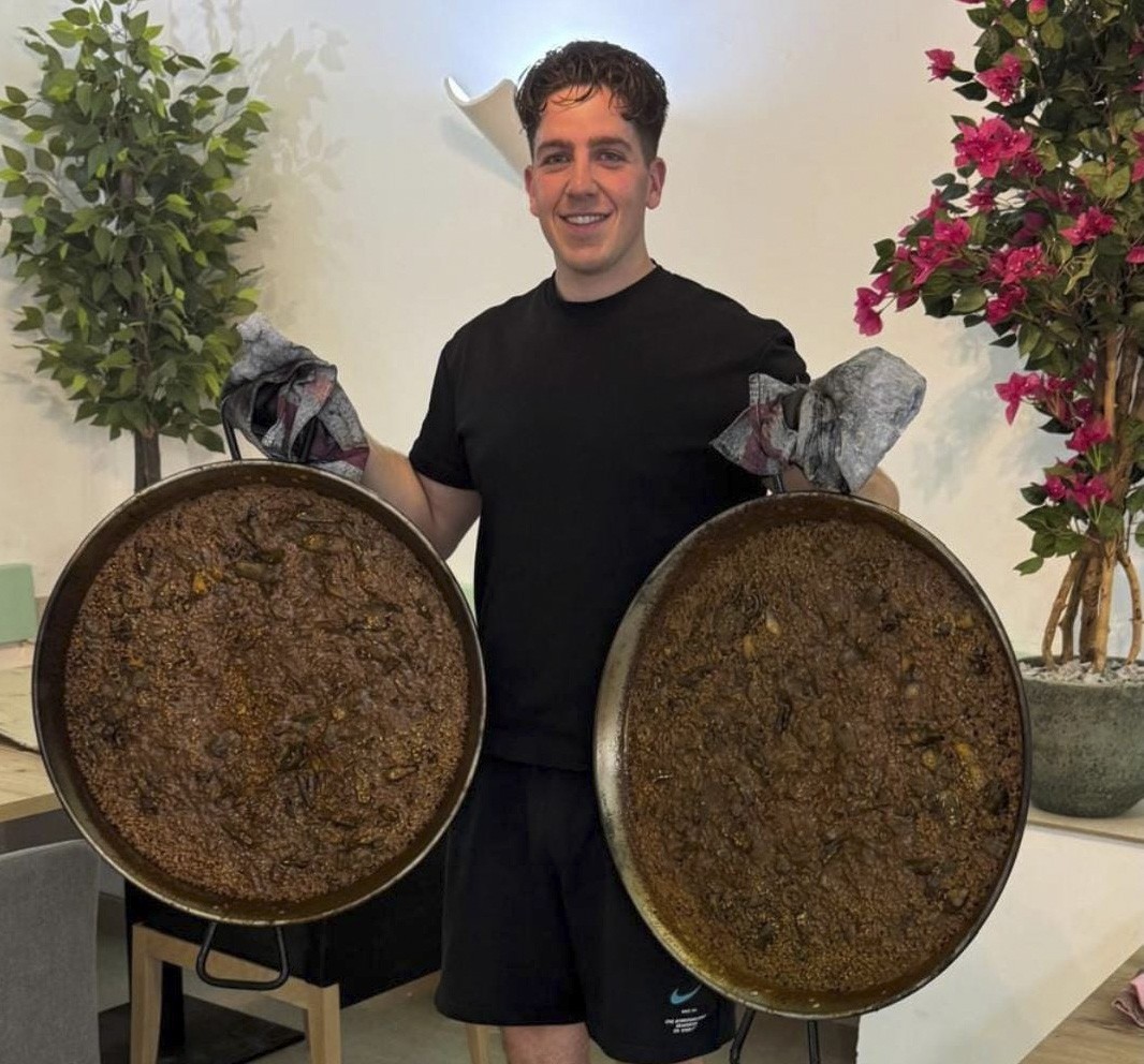 Benji, chef del restaurante, con dos paellas en la sala