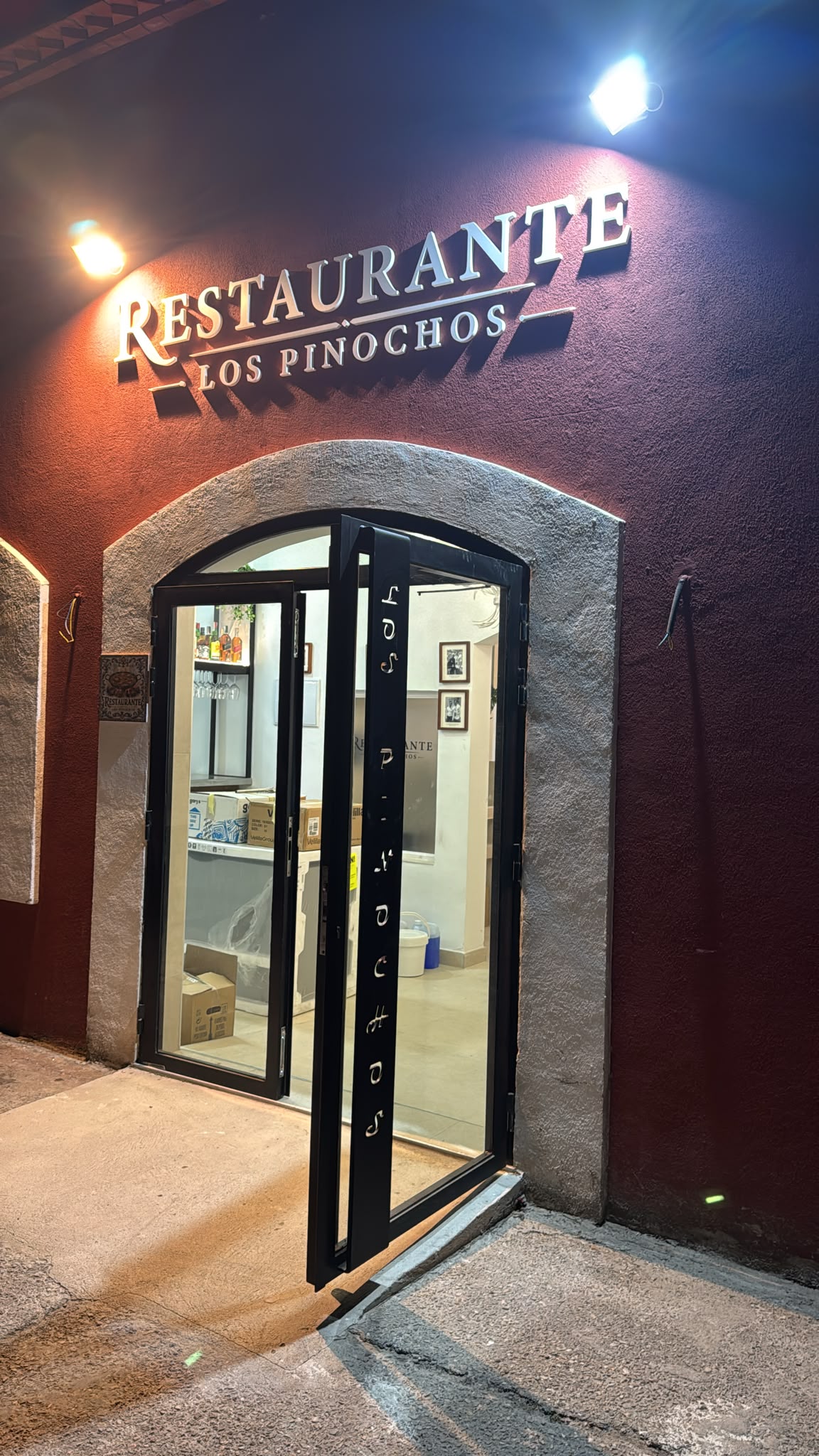 Entrance door of Restaurante Los Pinochos in Simancas (Valladolid), with the gold sign and the stone arch on the facade