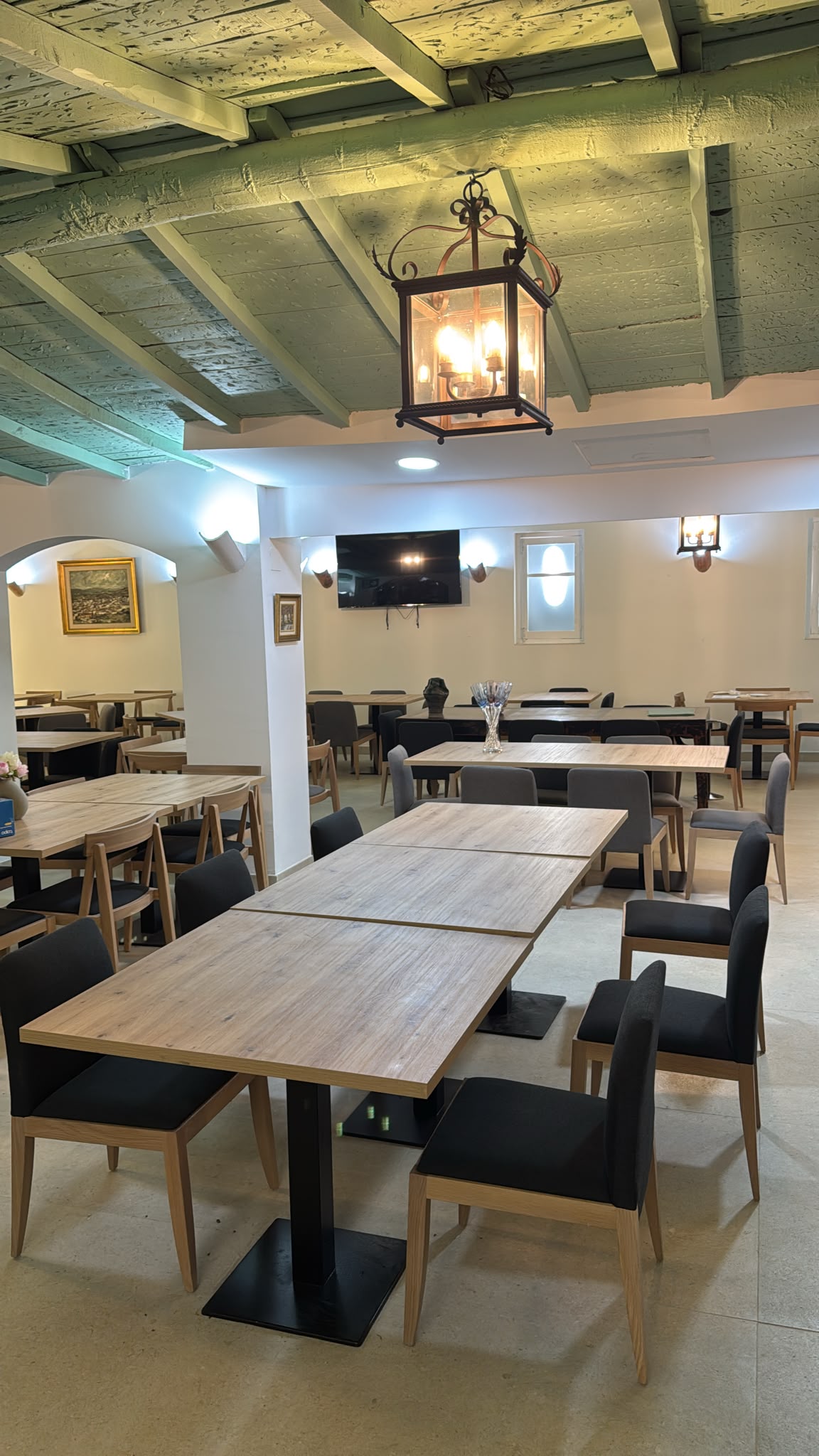 Sala del restaurante Los Pinochos, con vigas de madera, farol de forja y mesas
